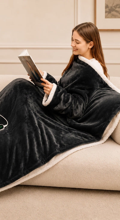 Kvinne leser i sofaen med Velora Varme varmeteppe, ermene på